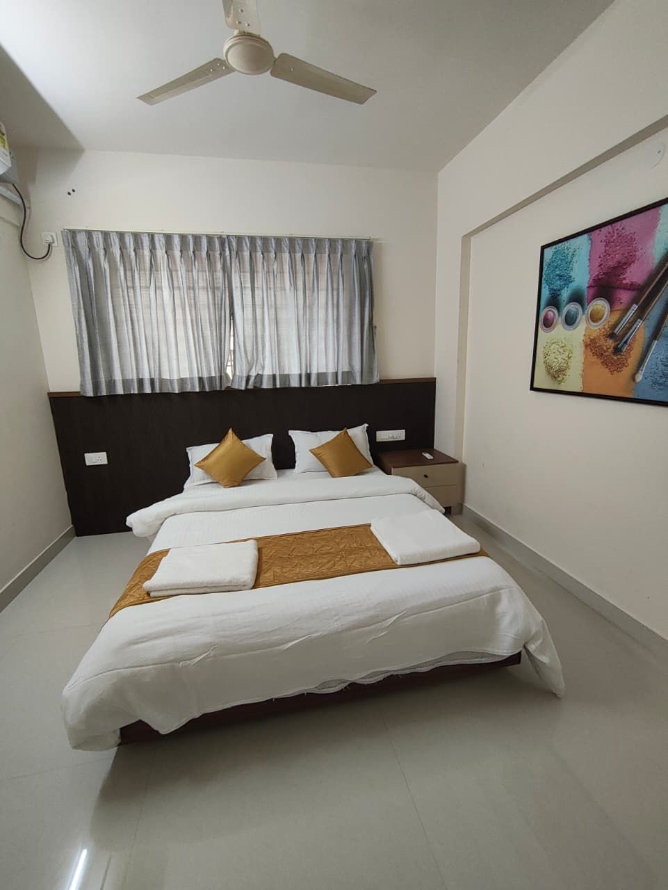 A neatly made bed with white and brown linens, a dark headboard, and a ceiling fan.