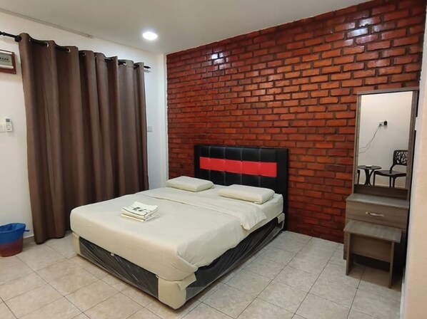 A bedroom with a brick wall, a bed with a red headboard, a small bedside table, and a mirror. - OYO 91257 Classic Homestay Keningau (Keningau)