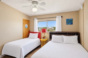 A hotel room with two beds, a ceiling fan, a window with curtains, and a view of the outside. - Gulf-Front Villa A-6 Pool Access Sleeps 7 (Saint George Island)