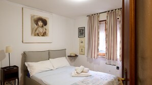 Una camera da letto con un letto, un comodino, una lampada, una finestra con tende e una porta.