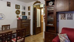 Zona pranzo con tavolo e sedie in legno, un divano rosso e un tappeto decorato.
