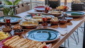 Een gedekte tafel met verschillende gerechten en drankjes, met uitzicht op een woestijnlandschap door grote ramen.