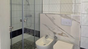 Un baño moderno con ducha de vidrio, un bidé y un inodoro.