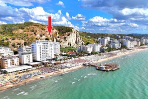 Un paisaje urbano costero con playa, edificios y un acantilado.