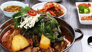 A bowl of stew with meat, potatoes, and leafy greens, surrounded by smaller bowls of side dishes. - Hotel Castle Soad Bogura (Bogra)