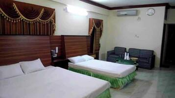 A hotel room with two beds, a sofa, and a small table.