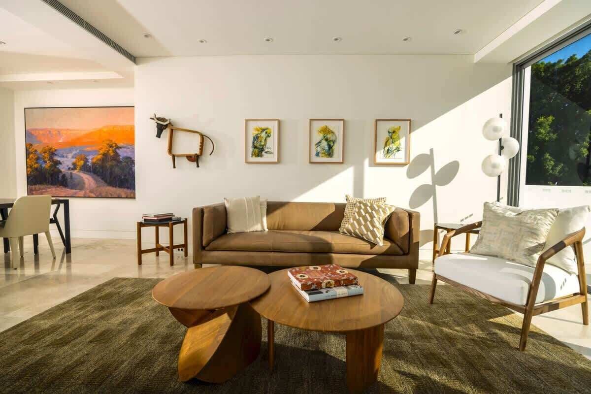 A modern living room with a sofa, two coffee tables, and artwork on the walls.