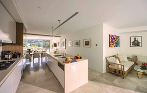 A modern kitchen with a central island, dining area with chairs, and a living space with a sofa and artwork. - Grand Double Bay Penthouse–Stunning Terrace & Pool (Double Bay)