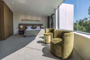 A modern bedroom with a large bed, a sofa, a small table, and a window with a view. - Grand Double Bay Penthouse–Stunning Terrace & Pool (Double Bay)