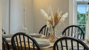 A dining table set with plates, glasses, and a vase with dried flowers. - Sweet 4BR Steps from UW | Prime Location @Seattle (Seattle)