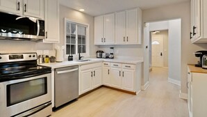 A modern kitchen with white cabinetry, a built-in oven, a dishwasher, and a window above the sink. - Sweet 4BR Steps from UW | Prime Location @Seattle (Seattle)