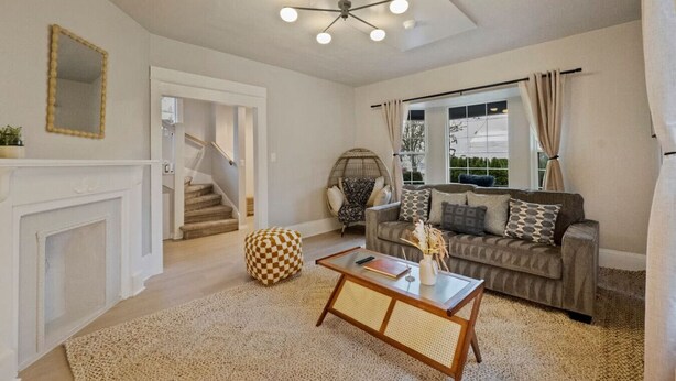 A living room with a sofa, coffee table, and a fireplace. There is a staircase leading to another room. - Sweet 4BR Steps from UW | Prime Location @Seattle (Seattle)