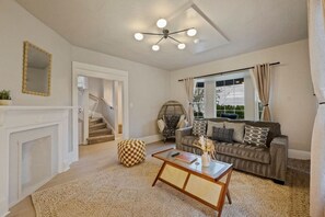 A living room with a sofa, coffee table, and a fireplace. There is a staircase leading to another room. - Sweet 4BR Steps from UW | Prime Location @Seattle (Seattle)