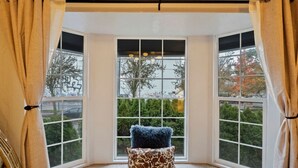 A corner room with large windows, a blue fluffy pillow, and a patterned cushion on the carpet. - Sweet 4BR Steps from UW | Prime Location @Seattle (Seattle)