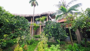 Een tropisch resort met rieten daken, weelderige begroeiing en palmbomen.