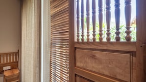 Een houten deur met een raam, een houten bank en een gordijn.