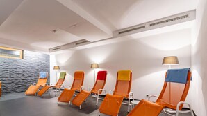 Una fila de sillones naranja con toallas, un muro de piedra y una lámpara de pie.
