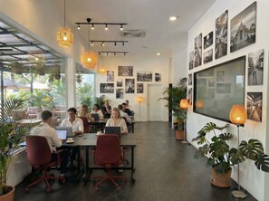 A modern office space with glass walls, multiple workstations, and potted plants.