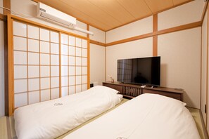 A hotel room with two beds, a TV, and a sliding shoji screen.