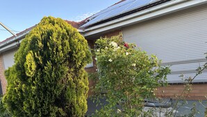 A residential building with a sloped roof, solar panels, and a garage door. - Three furnished bedrooms and two bathrooms house (Deer park)