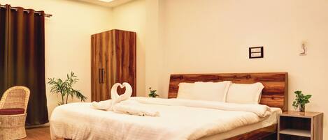 A neatly made bed with a wooden headboard, a wicker chair, and a small plant on the side.