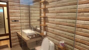 A bathroom with a wooden wall design, a glass shower enclosure, a white sink, and a toilet.