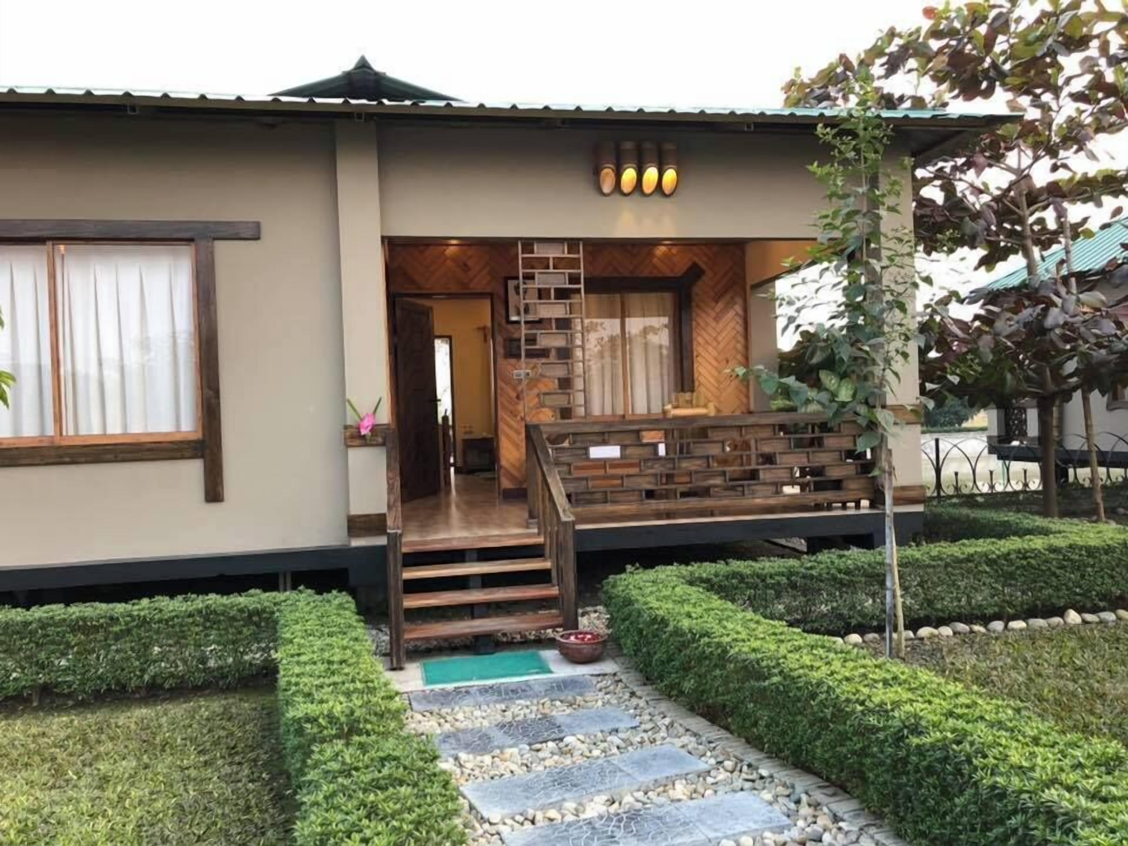 Un edificio moderno con una escalera de madera, un pequeño jardín y un césped bien cuidado.