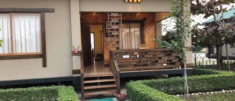 Un edificio moderno con una escalera de madera, un pequeño jardín y un césped bien cuidado.