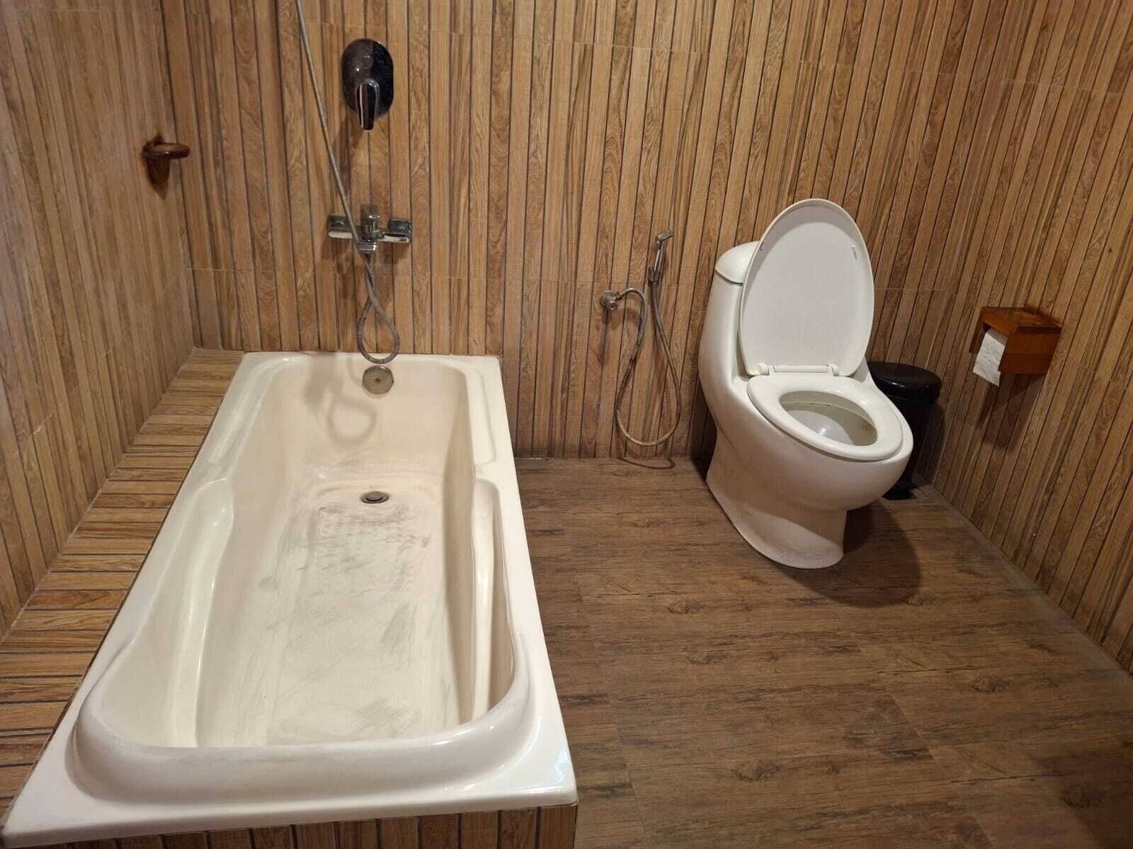 Une salle de bain avec une baignoire, des toilettes et un lambris en bois.