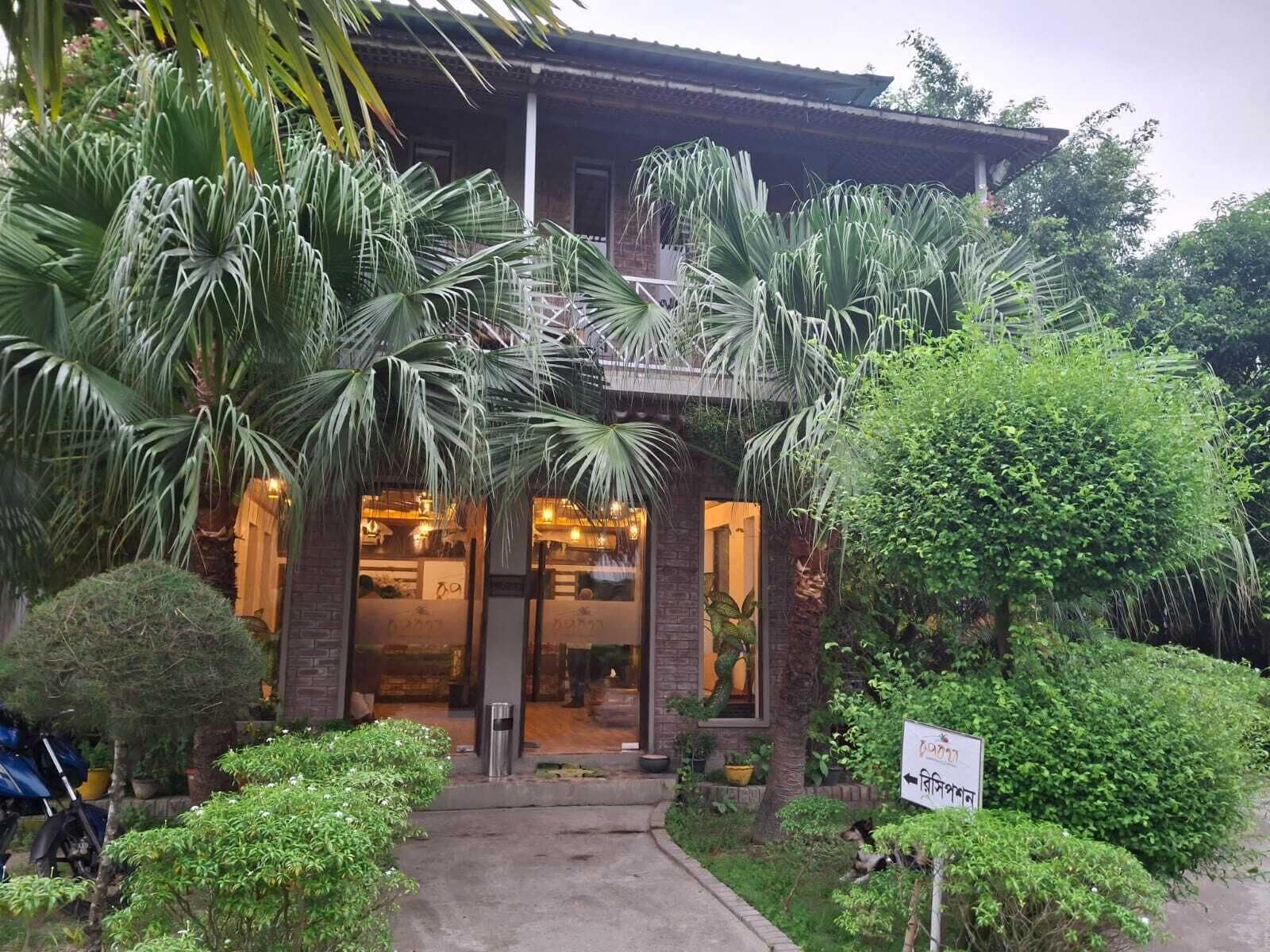 Un edificio con un acceso cubierto, rodeado de vegetación exuberante y palmeras.