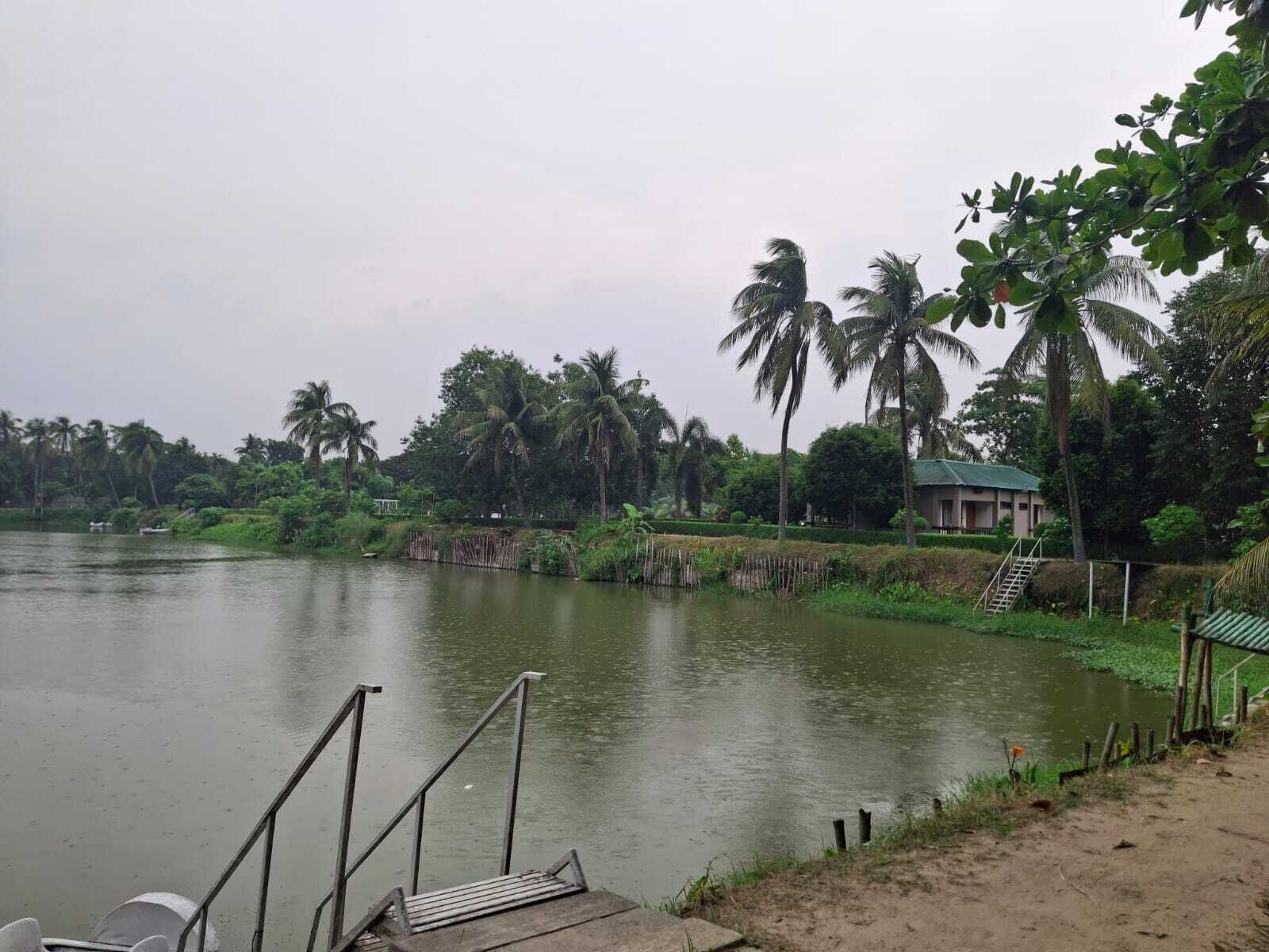 A calm lake with a wooden dock and a small building with a green roof.