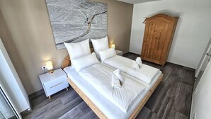 Ein ordentlich eingerichtetes Hotelzimmer mit einem großen Bett, einem Holzschrank und einem an der Wand befestigten Kunstwerk.
