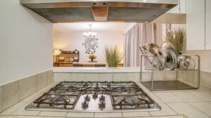 A kitchen with a gas stove, a stainless steel range hood, and a dish rack with pots and pans. - Home 1 Mi to UC Riverside: Families Welcome! (Riverside)