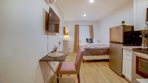 Ein kleines Schlafzimmer mit Bett, Nachttisch und einem Schreibtisch mit Stuhl.