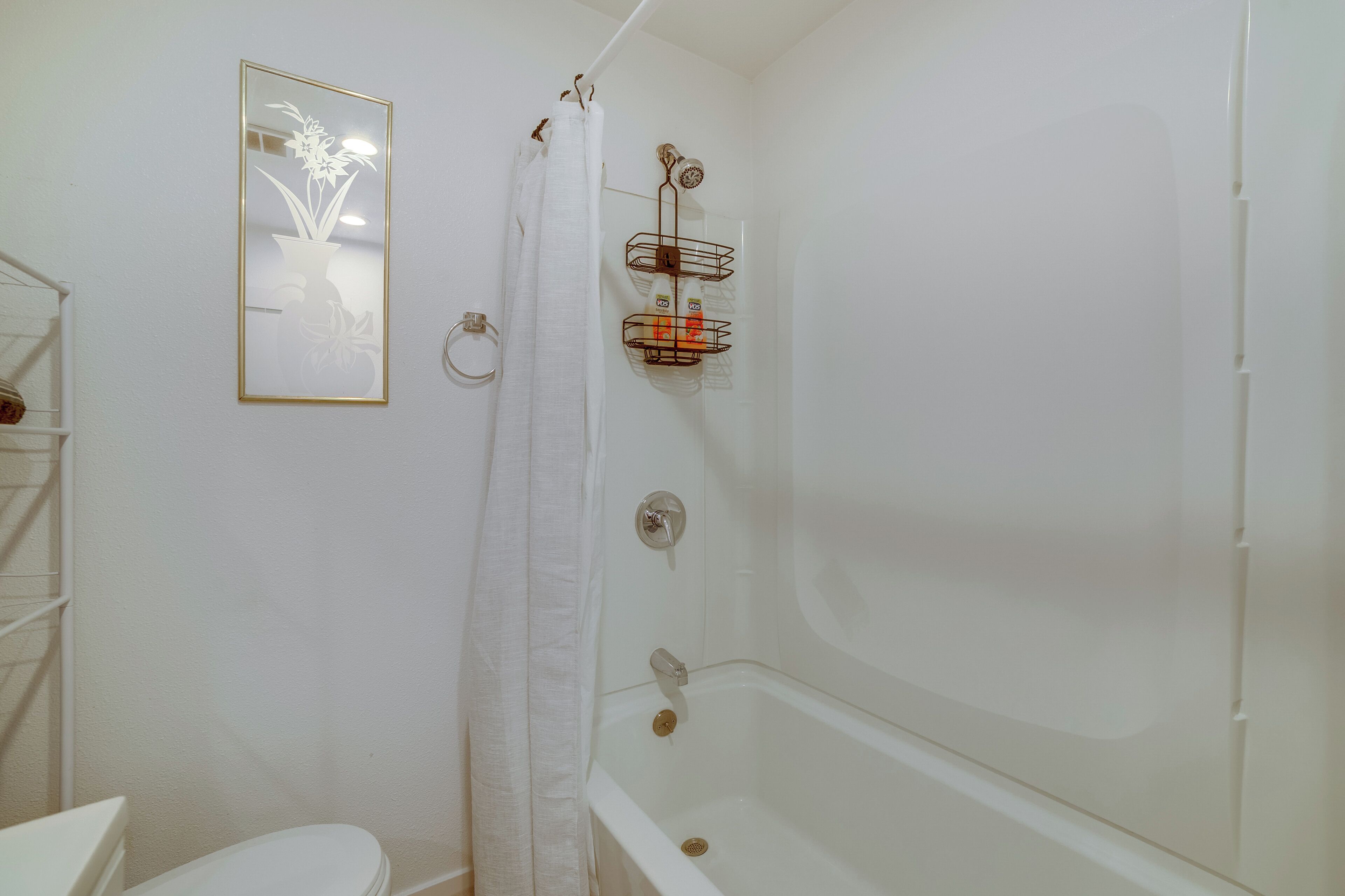 A bathroom with a bathtub, a toilet, a shower curtain, and a towel rack.