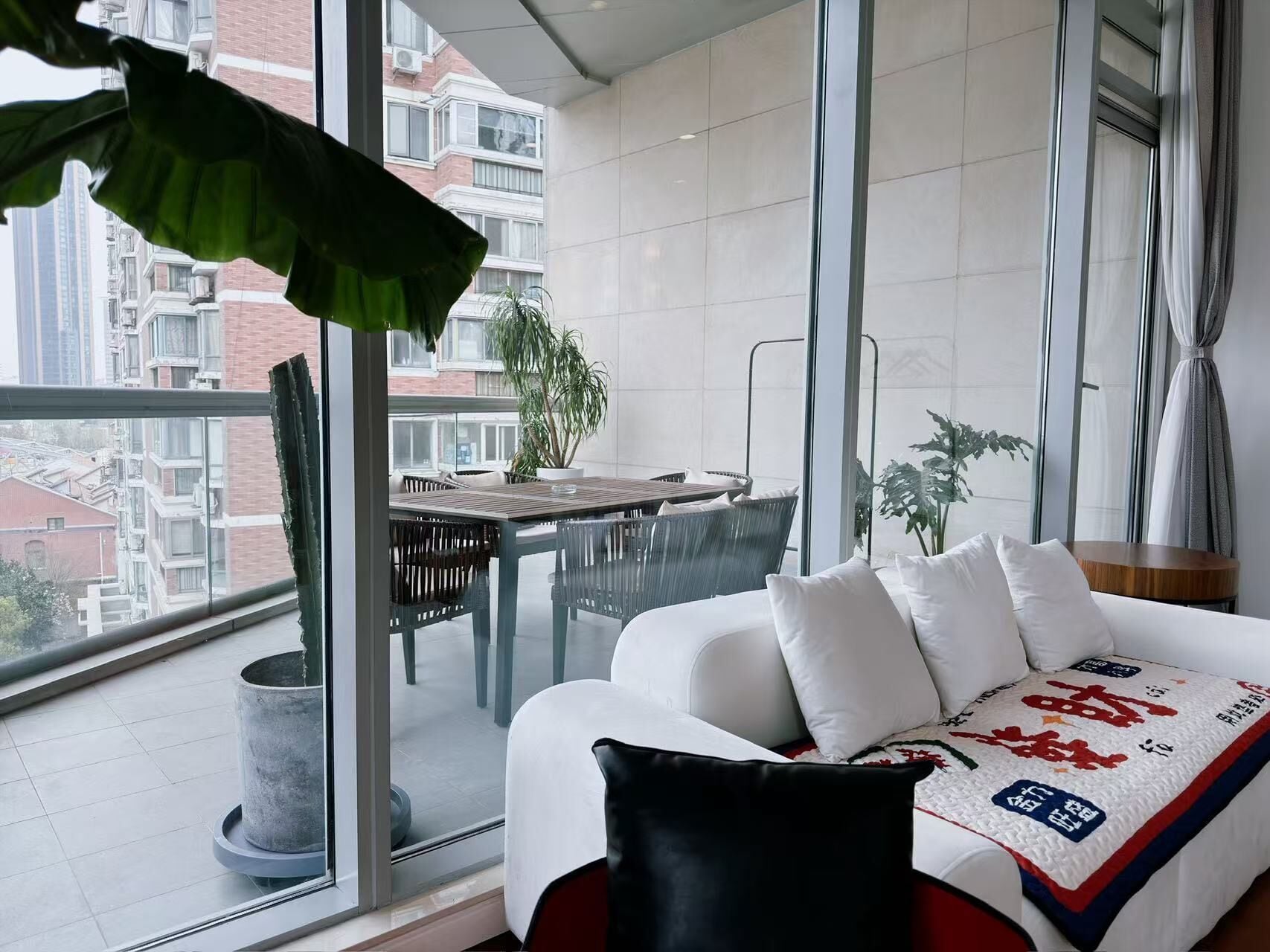 Un balcon avec une table à manger, des chaises et des plantes en pot.