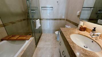 A bathroom with a bathtub, a sink, a toilet, and a glass shower enclosure.