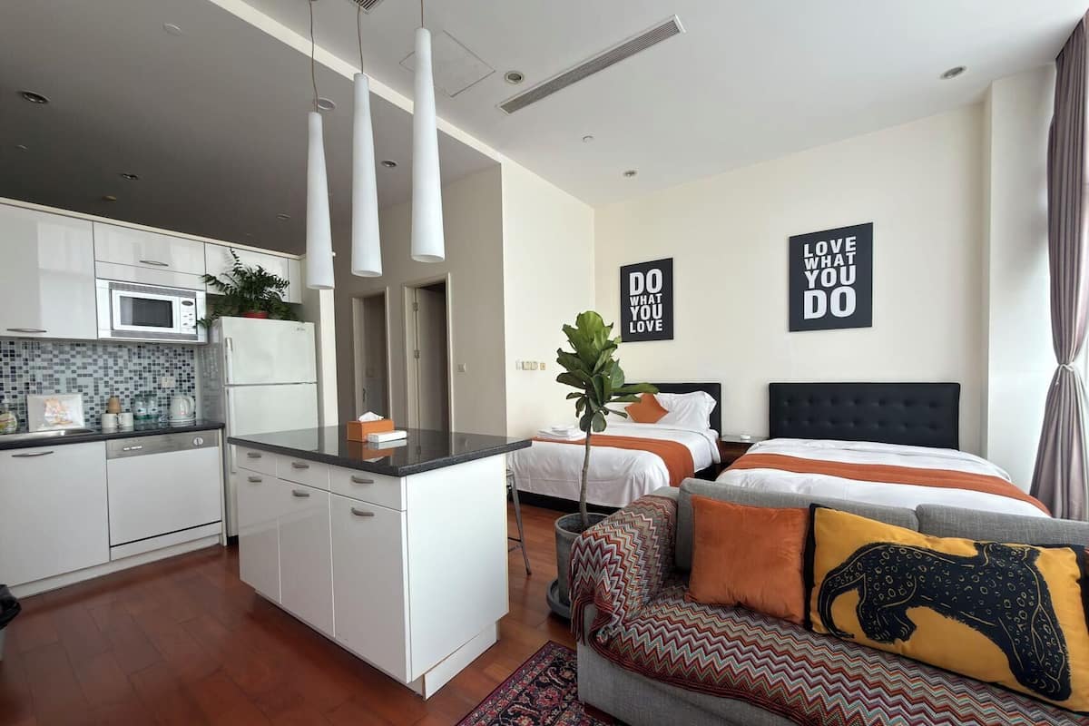 A modern apartment with a kitchenette, a dining area, a living room with a sofa and a bed.