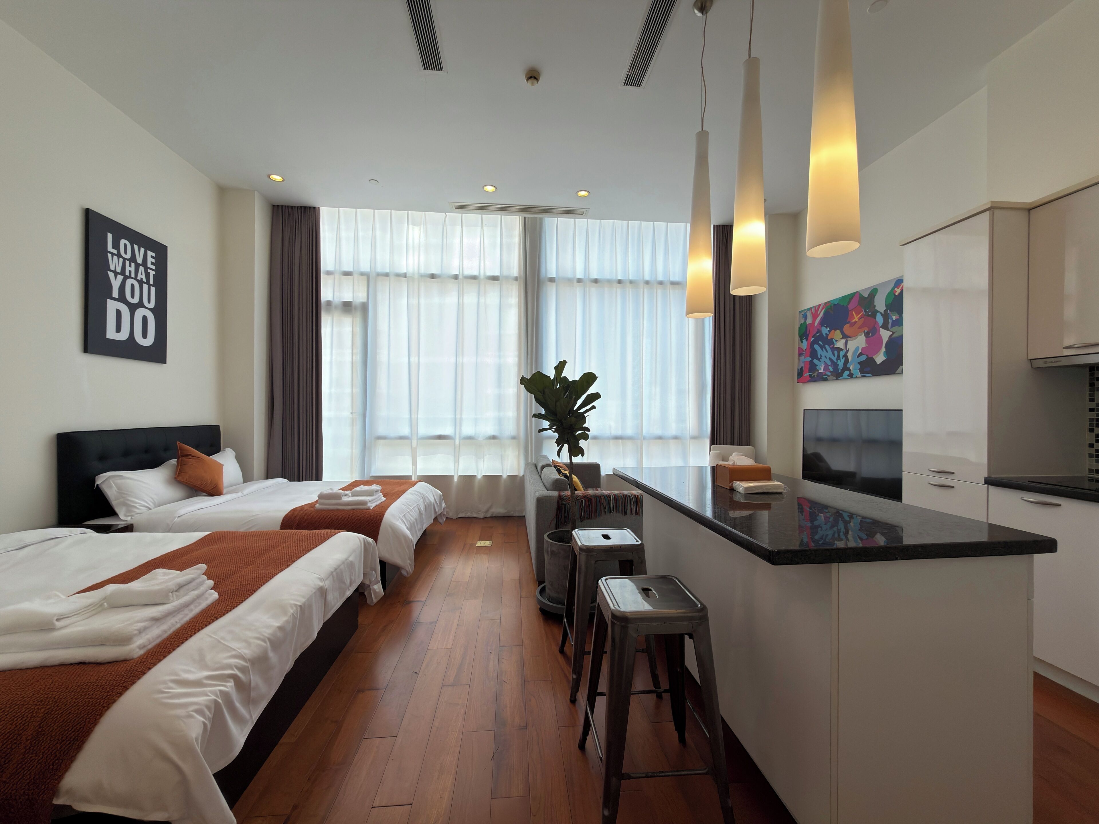 Ein Hotelzimmer mit Bett, Schreibtisch, Barbereich und einem großen Fenster mit Vorhängen.