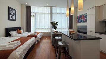 Ein Hotelzimmer mit Bett, Schreibtisch, Barbereich und einem großen Fenster mit Vorhängen.