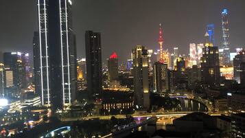 A nighttime cityscape with illuminated skyscrapers and a river.