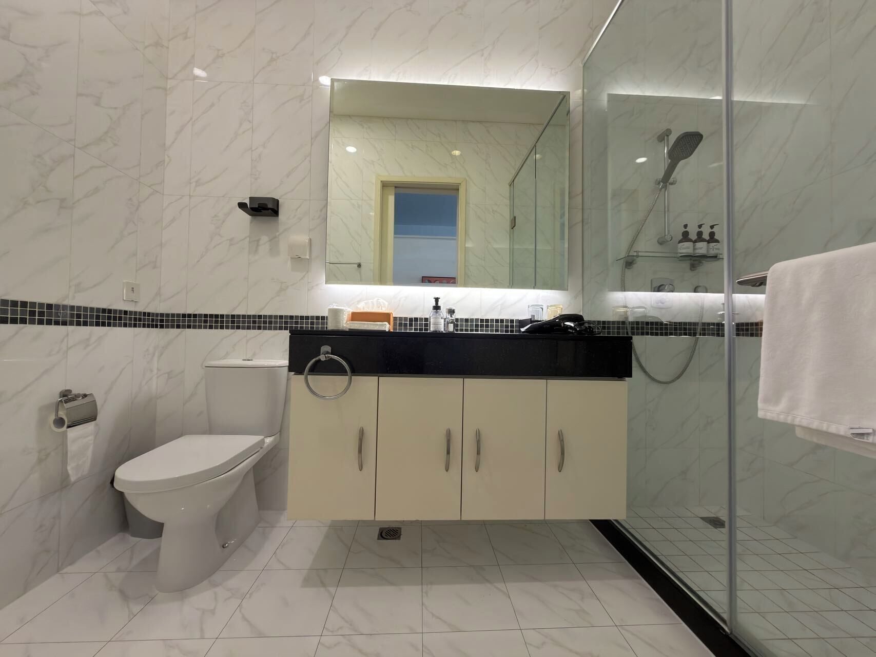 Un baño moderno con inodoro, lavamanos y ducha.