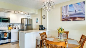 A modern kitchen with white cabinets, stainless steel appliances, and a central island with seating. - Oceanfront Studio w/ Gulf & Sunset Views From Bed! (Naples)