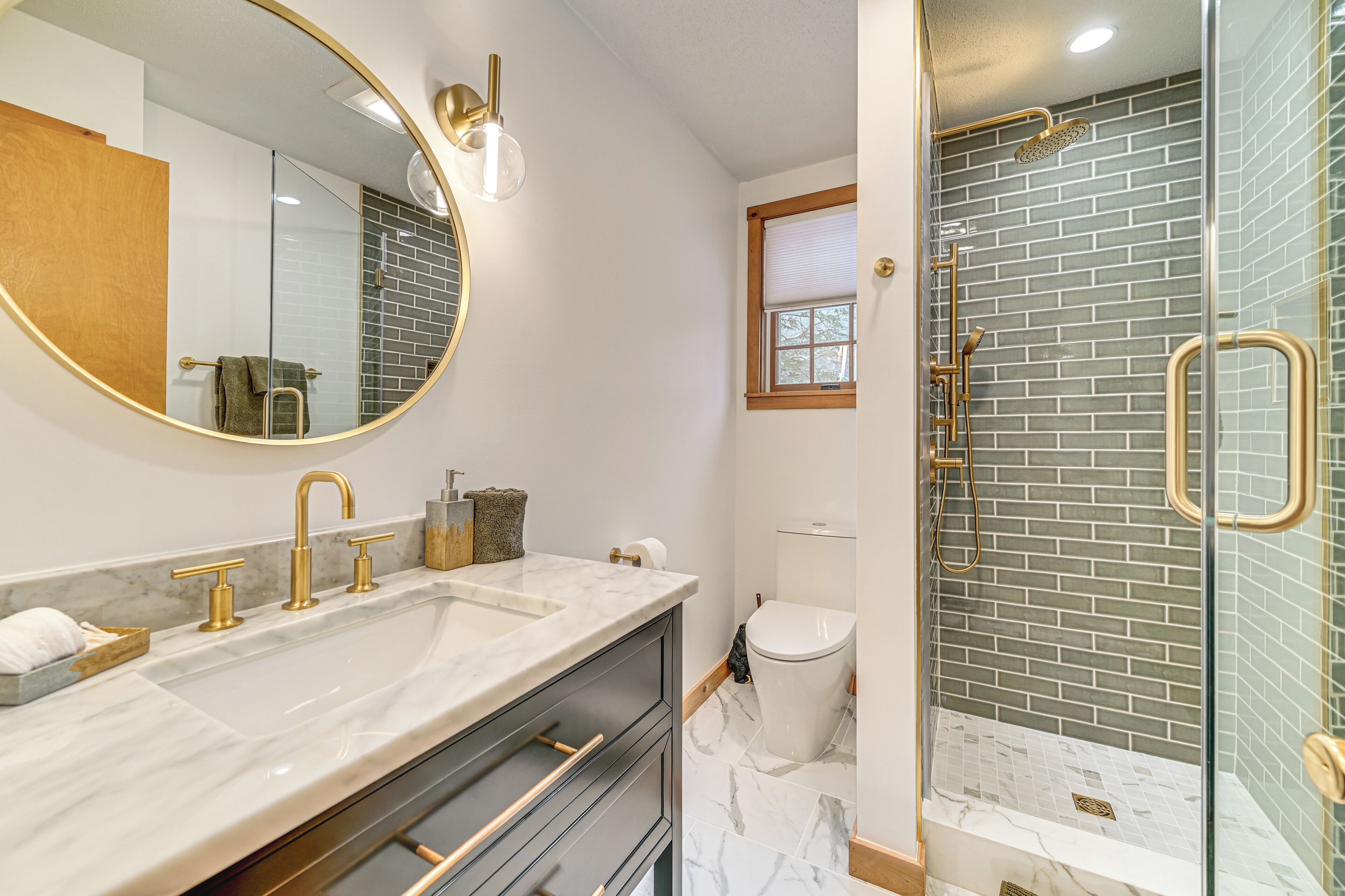 A bathroom with a double sink, a large mirror, a glass-enclosed shower, and a toilet.