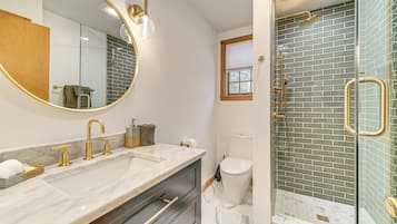 A bathroom with a double sink, a large mirror, a glass-enclosed shower, and a toilet.