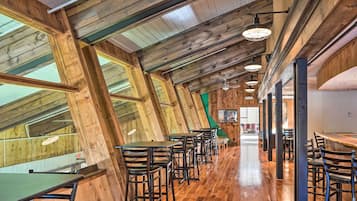 A restaurant with wooden beams, high ceilings, and a long counter with bar stools.