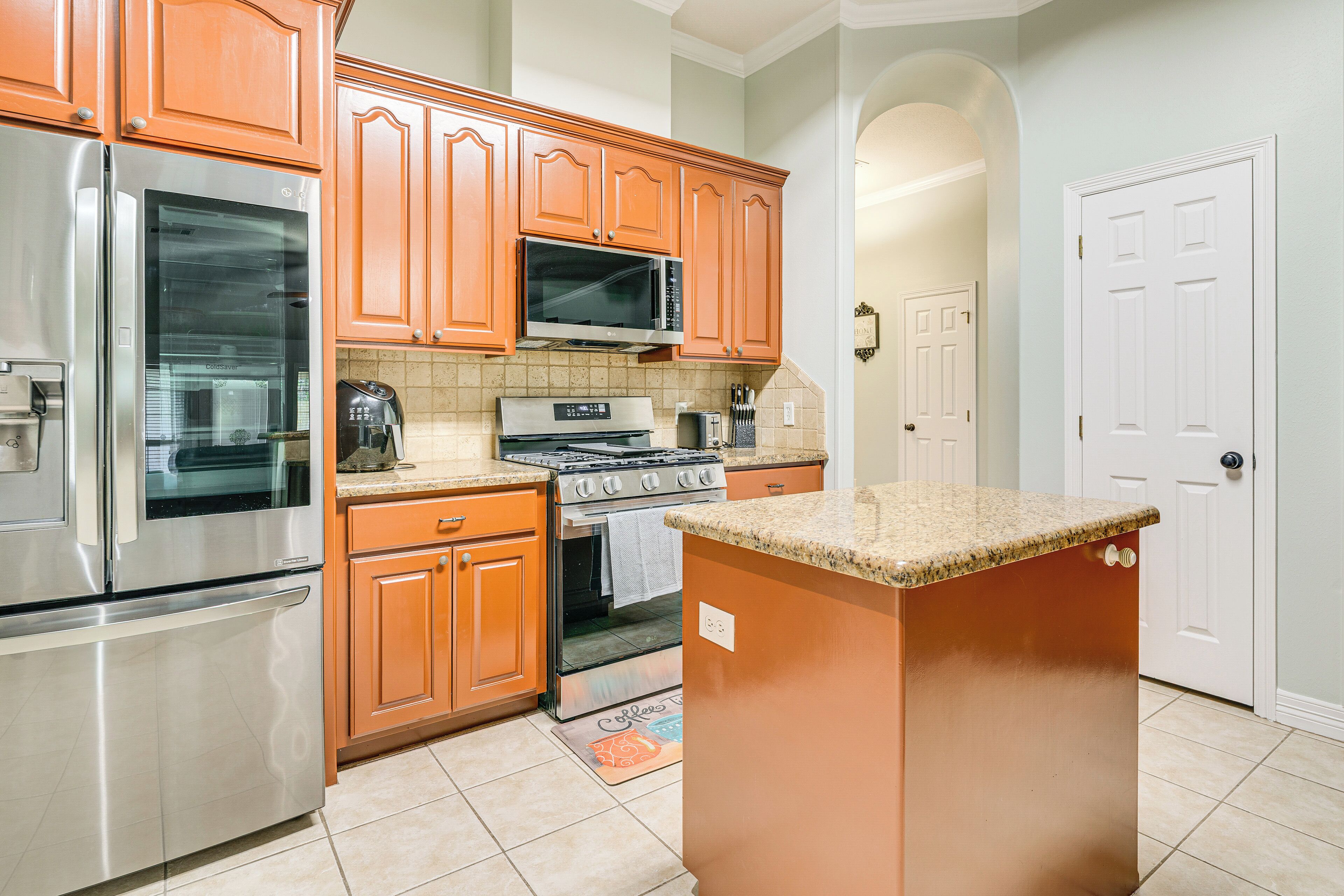 A kitchen with stainless steel appliances, wooden cabinets, and a granite countertop island.