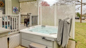 A hot tub with a step stool, a covered patio area, and a decorative fence. - Hike & Explore Western Mass: Peaceful Studio (Palmer)