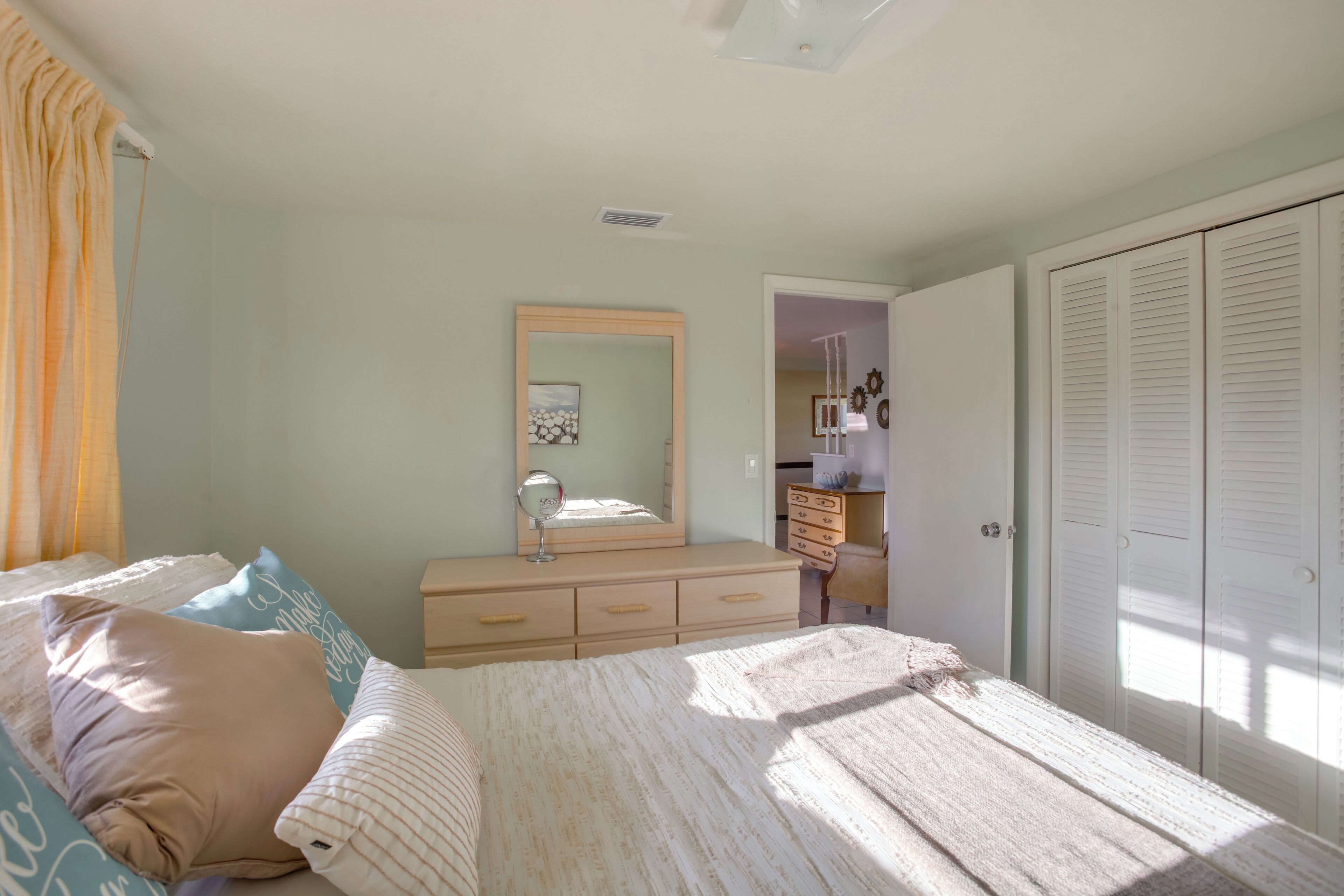 Ein Schlafzimmer mit Bett, Schminktisch, Spiegel und Kleiderschrank.