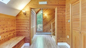 Un interior de madera con un banco, un letrero que dice “Lake House” y una vista a través de una puerta.